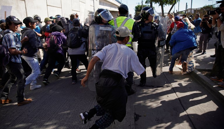Migrants break past a line of police as they run toward the Chaparral border crossing in Tijuana, Mexico, Sunday, Nov. 25, 2018, near the San Ysidro entry point into the U.S. More than 5,000 migrants are camped in and around a sports complex in Tijuana after making their way through Mexico in recent weeks via caravan.