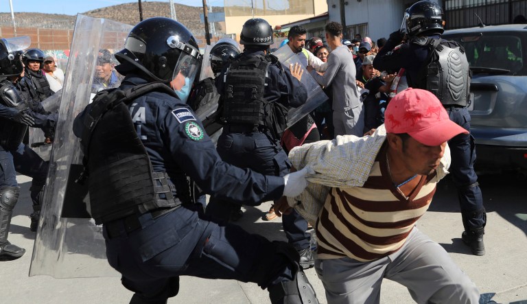 Migrants try to push past Mexican police on the Mexico-U.S. border at the Chaparral crossing in Tijuana, Mexico, Sunday, Nov. 25, 2018, as they try to reach the U.S. The mayor of Tijuana has declared a humanitarian crisis in his border city and says that he has asked the United Nations for aid to deal with the approximately 5,000 Central American migrants who have arrived in the city.