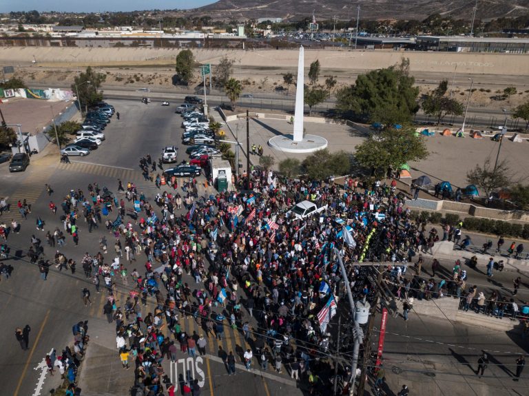 A group of migrants gather at the Chaparral border crossing in Tijuana, Mexico, Sunday, Nov. 25, 2018, as they try to pressure their way into the U.S.
