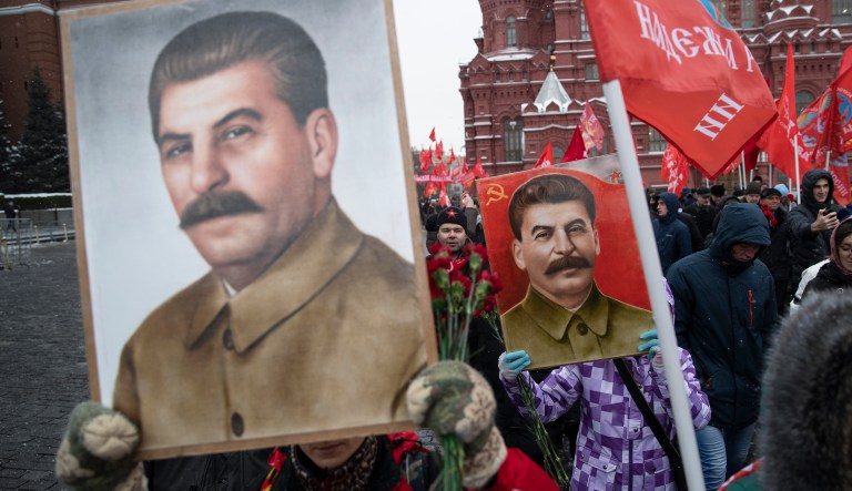 Communist supporters hold portraits of Soviet leader Josef Stalin as they queue to lay flowers at the grave of Stalin to mark the 139th anniversary of his birth, Moscow's Red Square, Russia, Friday, Dec. 21, 2018.