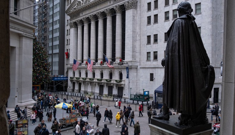 People stand near a statue of George Washington, adjacent to the New York Stock Exchange, Saturday, Dec. 22, 2018, at the closed Federal Hall National Memorial in New York.