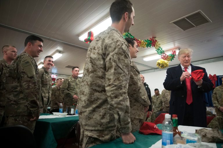 President Trump signs a "Make America Great Again" hat as he visits with members of the military at a dining hall at al-Asad Air Base, Iraq, Wednesday, Dec. 26, 2018.
