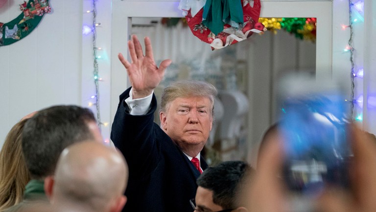President Trump waves as he leaves a dining hall after visiting members of the military at Al Asad Air Base, Iraq.