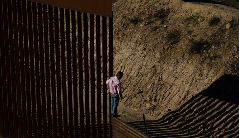A migrant stands on the border fence before jumping to get into the U.S. side to San Diego, Calif., from Tijuana, Mexico, Friday, Dec. 28, 2018.