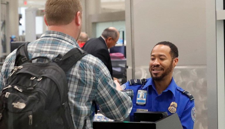 A Transportation Security Administration employee helps air travelers check in at a TSA security checkpoint at Hartsfield Jackson Atlanta International Airport Monday, Jan. 7, 2019, in Atlanta.
