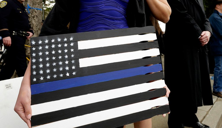 Liliana Teague, 11, holds a thin blue line sign next to her mother Stephanie after funeral services for Davis Police Officer Natalie Corona in Davis, Calif.