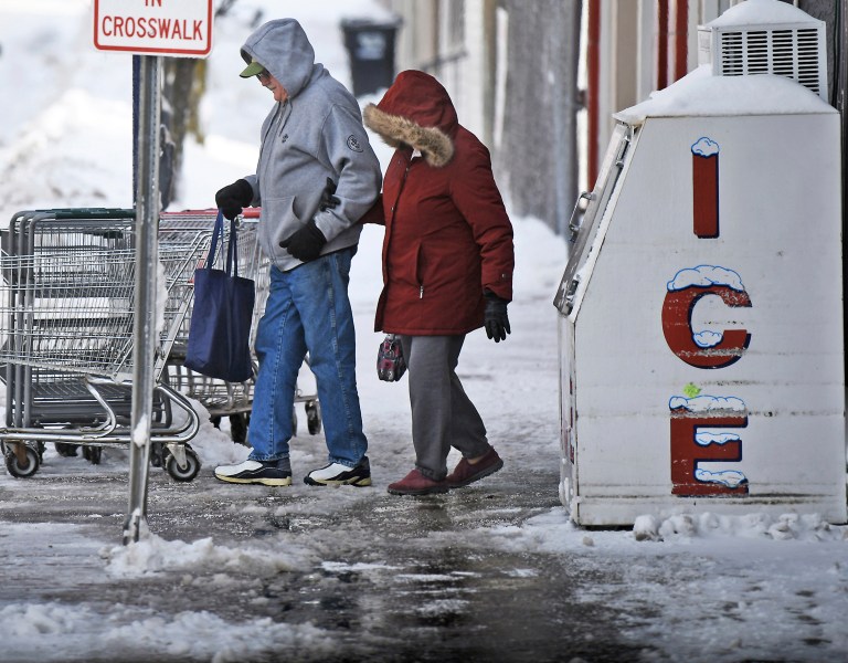 A man and woman walk outside in a polar vortex as they leave Zazzera's Supermarket on Main Street in Forest City, Pa.