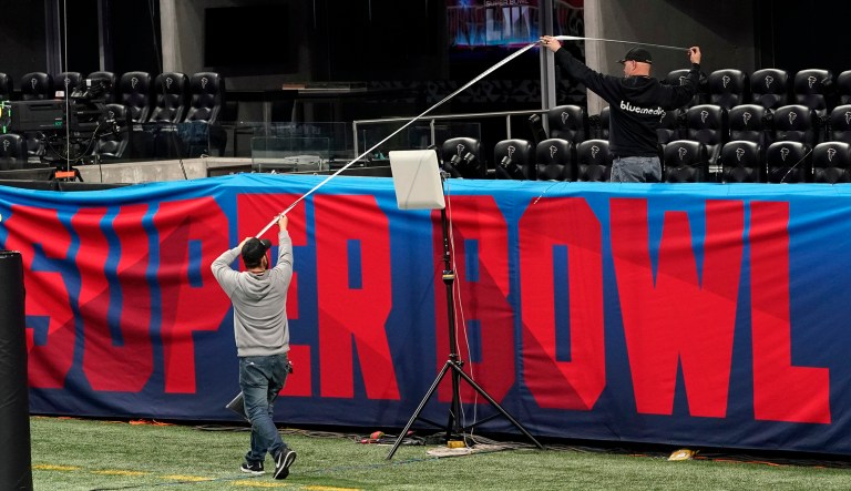 Workers use a tape measure as they hang a sign inside Mercedes-Benz Stadium for the NFL Super Bowl 53 football game Tuesday, Jan. 29, 2019, in Atlanta.
