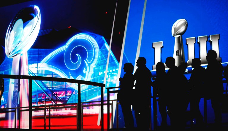 Fans line up in front of a big screen to have their photo taken with the Vince Lombardi Trophy on display at the NFL Experience ahead of Sunday's Super Bowl 53 football game between the Los Angeles Rams and New England Patriots.