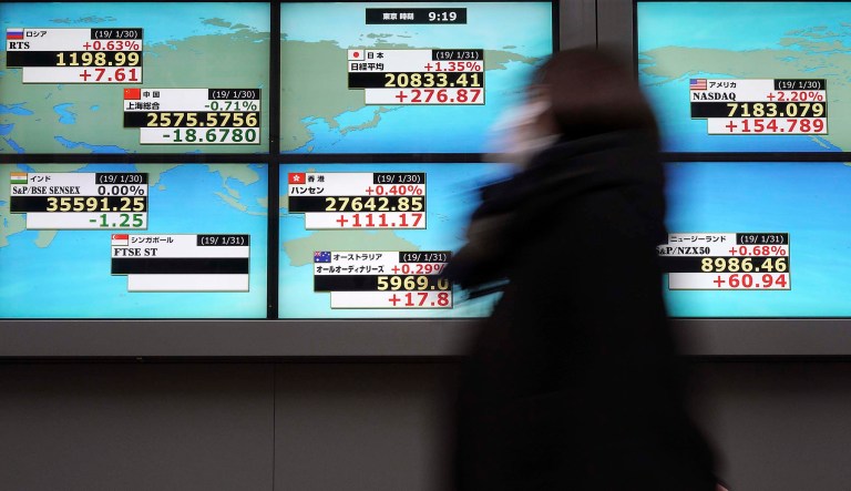 A woman walks past an electronic stock board showing Japan's Nikkei 225 index and other country's index at a securities firm in Tokyo Thursday, Jan. 31, 2019.