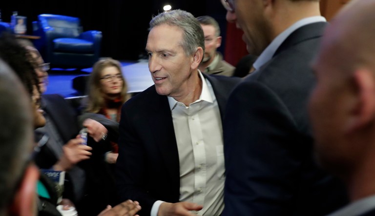Former Starbucks CEO Howard Schultz shakes hands after speaking.
