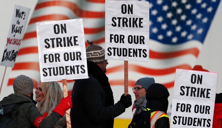 Teachers carry placards as they walk a picket line outside South High School early Monday, Feb. 11, 2019, in Denver. 