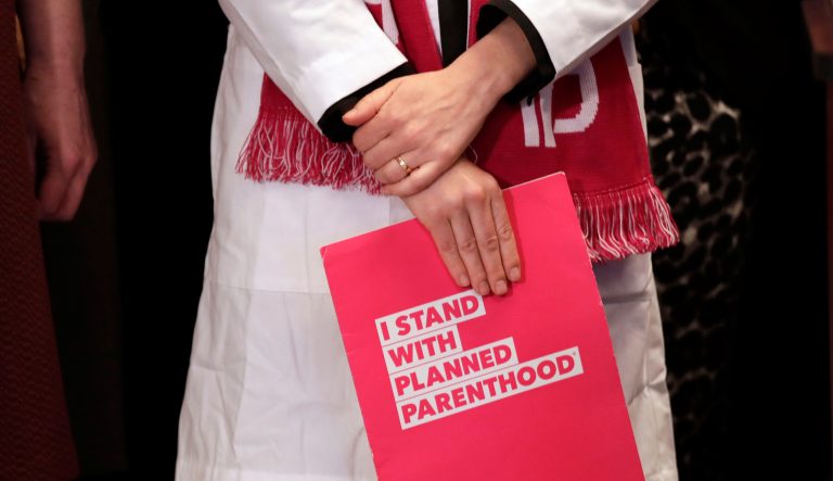 Dr. Erin Berry, Washington State Medical Director for Planned Parenthood of the Great Northwest and the Hawaiian Islands, holds a folder as she listens at a news conference announcing a lawsuit challenging the Trump administration's Title X "gag rule" Monday, Feb. 25, 2019, in Seattle.