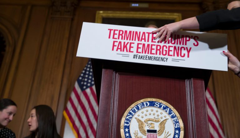 An aide places a placard on the podium before a media availability about a resolution to block President Donald Trump's emergency border security declaration on Capitol Hill, Monday, Feb. 25, 2019 in Washington. House Democrats have introduced a resolution to block the national emergency declaration that President Donald Trump issued last week to fund his long-sought wall along the U.S-Mexico border, setting up a fight that could result in Trump's first-ever veto. 
