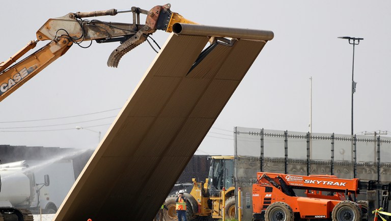 A border wall prototype falls during demolition at the border between Tijuana, Mexico, and San Diego.