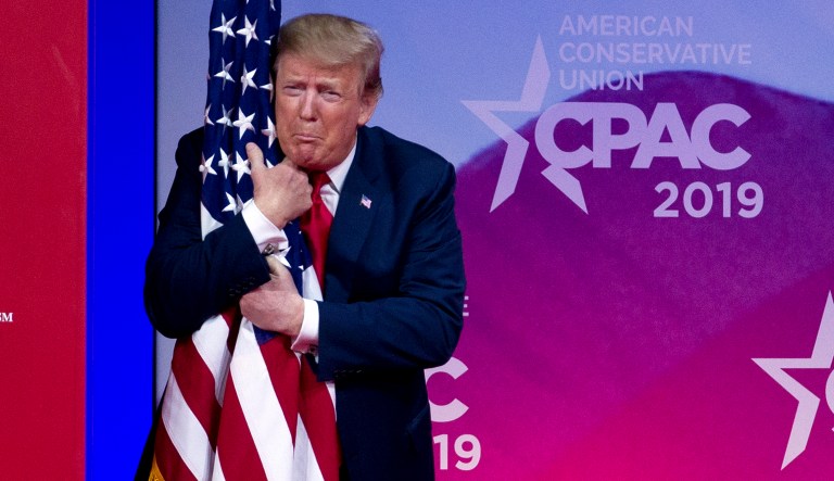 President Donald Trump hugs the American flag as he arrives to speak at Conservative Political Action Conference, CPAC 2019, in Oxon Hill, Md., Saturday, March 2, 2019. 