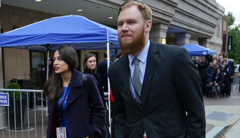 Rep.-elect Alexandria Ocasio-Cortez, D-NY., left, is seen leaving orientation session for new members of Congress, Tuesday, Nov. 13, 2018, in Washington. Walking alongside Ocasio-Cortez is Riley Roberts, right.