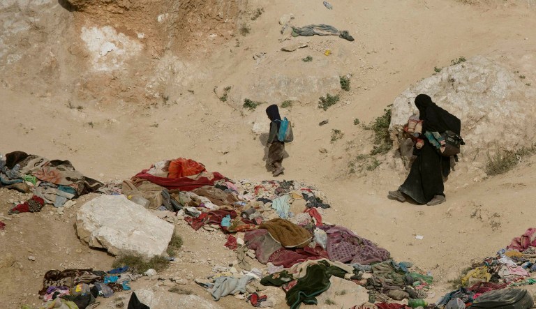 A woman and her children, who left the besieged Islamic State-held village of Baghouz, Syria, scramble over a rocky hillside to be checked by U.S-backed Syrian Democratic Forces Thursday.
