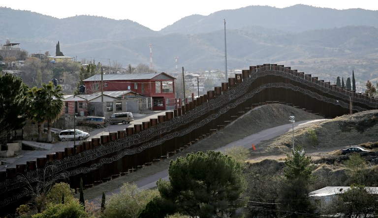 In this March 2, 2019 file photo, a razor-wire-covered border wall separates Nogalas, Mexico, at left, and Nogales, Ariz.