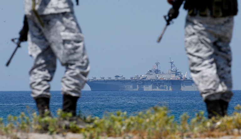 Philippine Navy personnel watch as US Navy's multipurpose amphibious assault ship USS WASP cruises in the background during the Joint US-Philippine Military Exercise flag dubbed "Balikatan 2019" Thursday, April 11, 2019, off San Antonio, Zambales province northwest of Manila, Philippines.