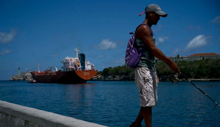A fisherman walks on the Malecon seawall where an oil tanker can be see in the background in Havana, Cuba, Wednesday, April 17, 2019. Washington has sanctioned Venezuelaâs oil industry and shipping companies that move Venezuelan oil to Cuba. 
