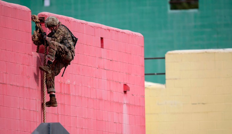 An Army Ranger climbs down from a rooftop during the urban assault portion of the Best Ranger competition in Fort Benning, Georgia.
