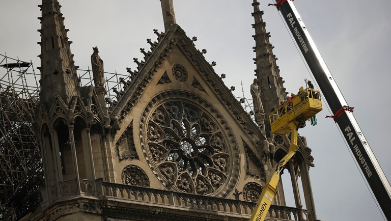 Technicians work in a crane next to the Notre Dame cathedral in Paris.