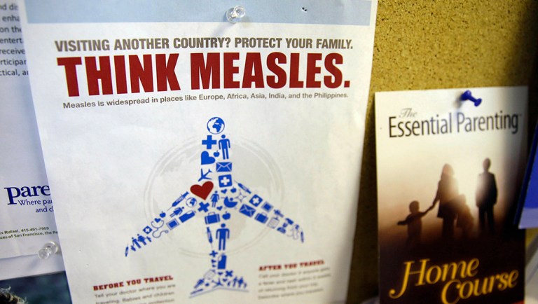 A flyer educating parents about measles is displayed on a bulletin board.