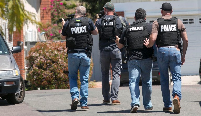 Heavily armed San Diego police officers approach a house thought to be the home of 19 year-old John T. Earnest, who is a suspect in the shooting of several people in a Poway synagogue, on Saturday, April 27, 2019, in San Diego, Calif. A gunman used an AR-type assault weapon to shoot worshippers at Chabad of Poway, San Diego County Sheriff William Gore said.