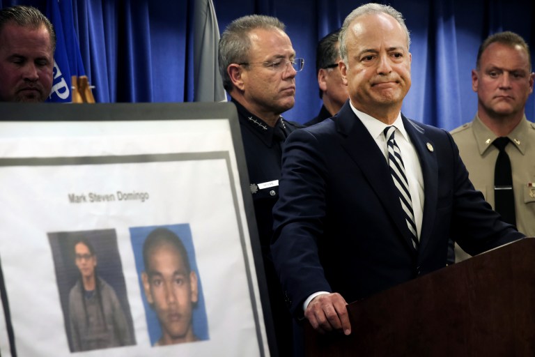 United States Attorney Nick Hanna stands next to photos of Mark Steven Domingo, during a news conference in Los Angeles.