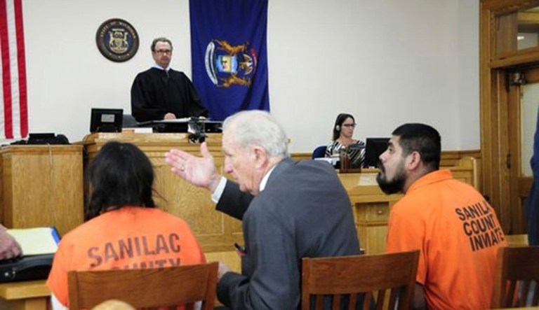 Interpreter Victor Moigis (center) explains District Judge Gregory Ross' instructions to Francisca Vargas-Castillo during a court hearing in the Sanilac District Court in Sandusky, Mich.
