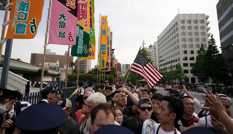 People wait for the arrival of President Trump outside the national sumo stadium in Tokyo.