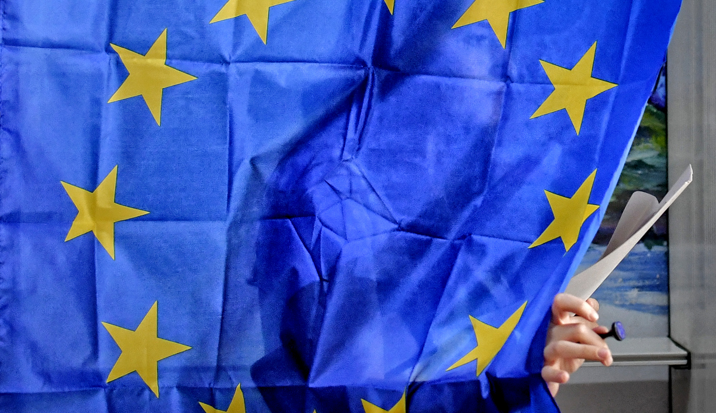 A woman exits a voting cabin with curtains depicting the European Union in Baleni, Romania.