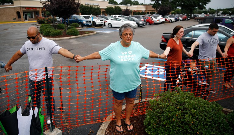 Lisa Dunaway, center, of Virginia Beach, Va., holds hands with gatherers during a vigil in response to a shooting at a municipal building in Virginia Beach, Va., Saturday, June 1, 2019. A longtime city employee opened fire at the building Friday before police shot and killed him, authorities said.