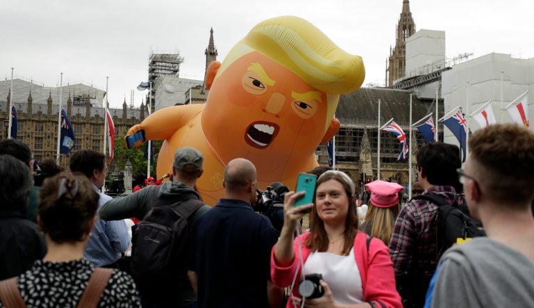 A woman takes a selfie as the 'Trump Baby' blimp is inflated in Parliament Square in central London as people start to gather to demonstrate against the state visit of President Donald Trump, Tuesday, June 4, 2019. Trump will turn from pageantry to policy Tuesday as he joins British Prime Minister Theresa May for a day of talks likely to highlight fresh uncertainty in the allies' storied relationship. 
