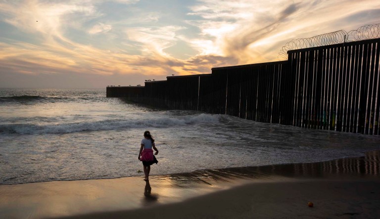 A girl plays along the border wall, right, separating San Diego from Tijuana, Mexico, where it meets the Pacific Ocean, Tuesday, June 11, 2019, in Tijuana.