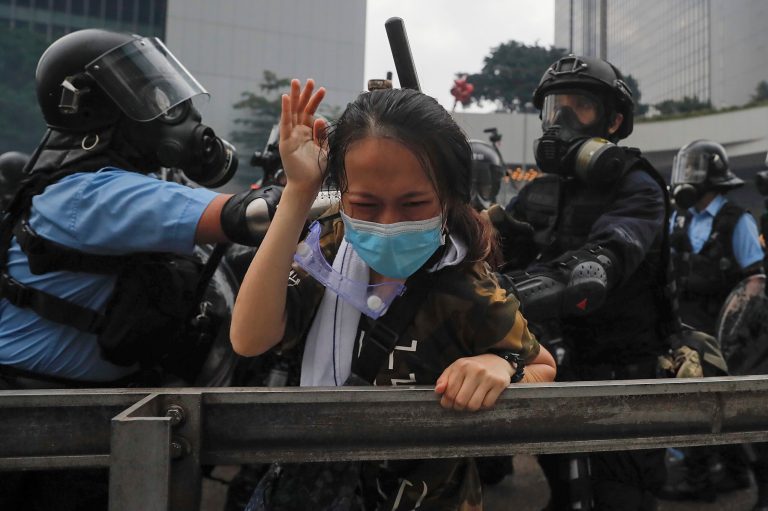 A protester reacts as she is tackled by riot police.