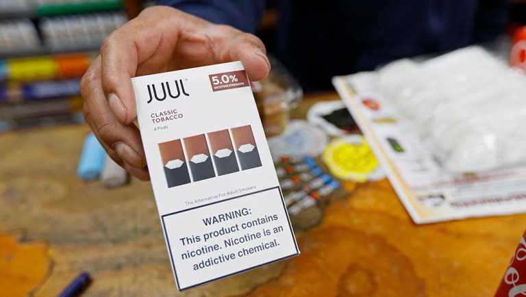A cashier displays a packet of tobacco-flavored Juul pods.
