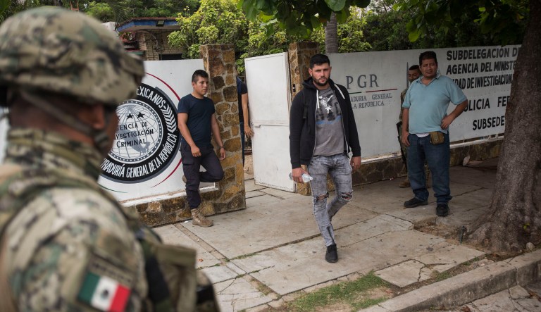 A man without legal permission to be in Mexico leaves an office of the Attorney General before being sent to Tapachula in an immigration van, as members of the National Guard stand watch in Arriaga, Mexico.