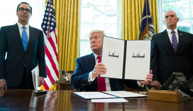 In this Monday, June 24, 2019 photo, President Donald Trump holds up a signed executive order to increase sanctions on Iran, accompanied by Treasury Secretary Steve Mnuchin, left, and Vice President Mike Pence, in the Oval Office of the White House, in Washington. 