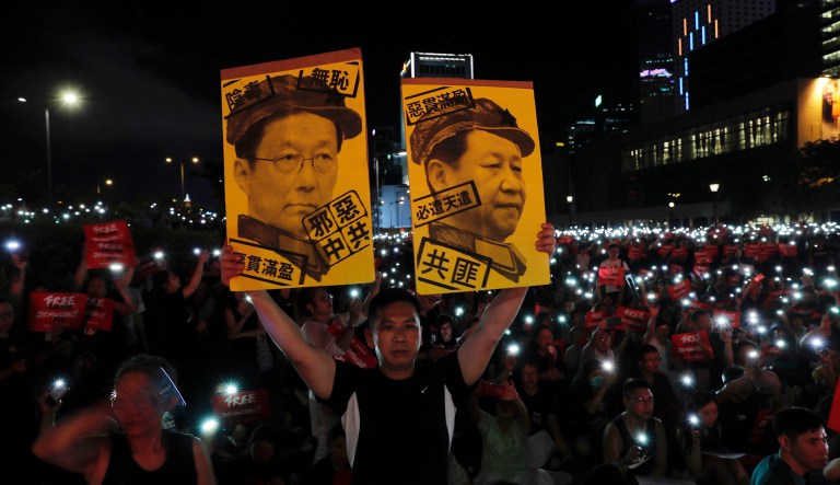A protester hold up cards caricaturing Chinese President Xi Jinping at right and China Vice Premier Han Zheng at left with the words "Communist Robbers", "Evil Chinese Communists" during a rally in Hong Kong.