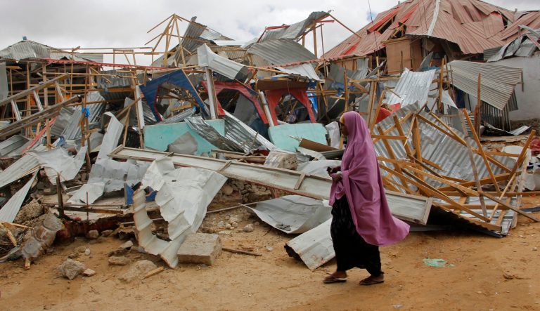 A Woman walks near destroyed buildings after a car bomb detonated in Mogadishu, Somalia, Monday July 8, 2019. 