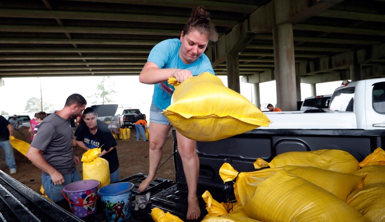 Tiffany Delee tosses a filled sandbag into the back of the family truck, while her husband Mike Delee, left, readies to tie up another bag, in Morgan City, Louisiana.