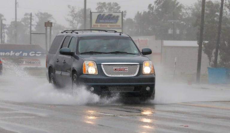 A vehicle kicks up a water spray as winds and rain increase in Morgan City, Louisiana, Saturday morning as Barry approaches.