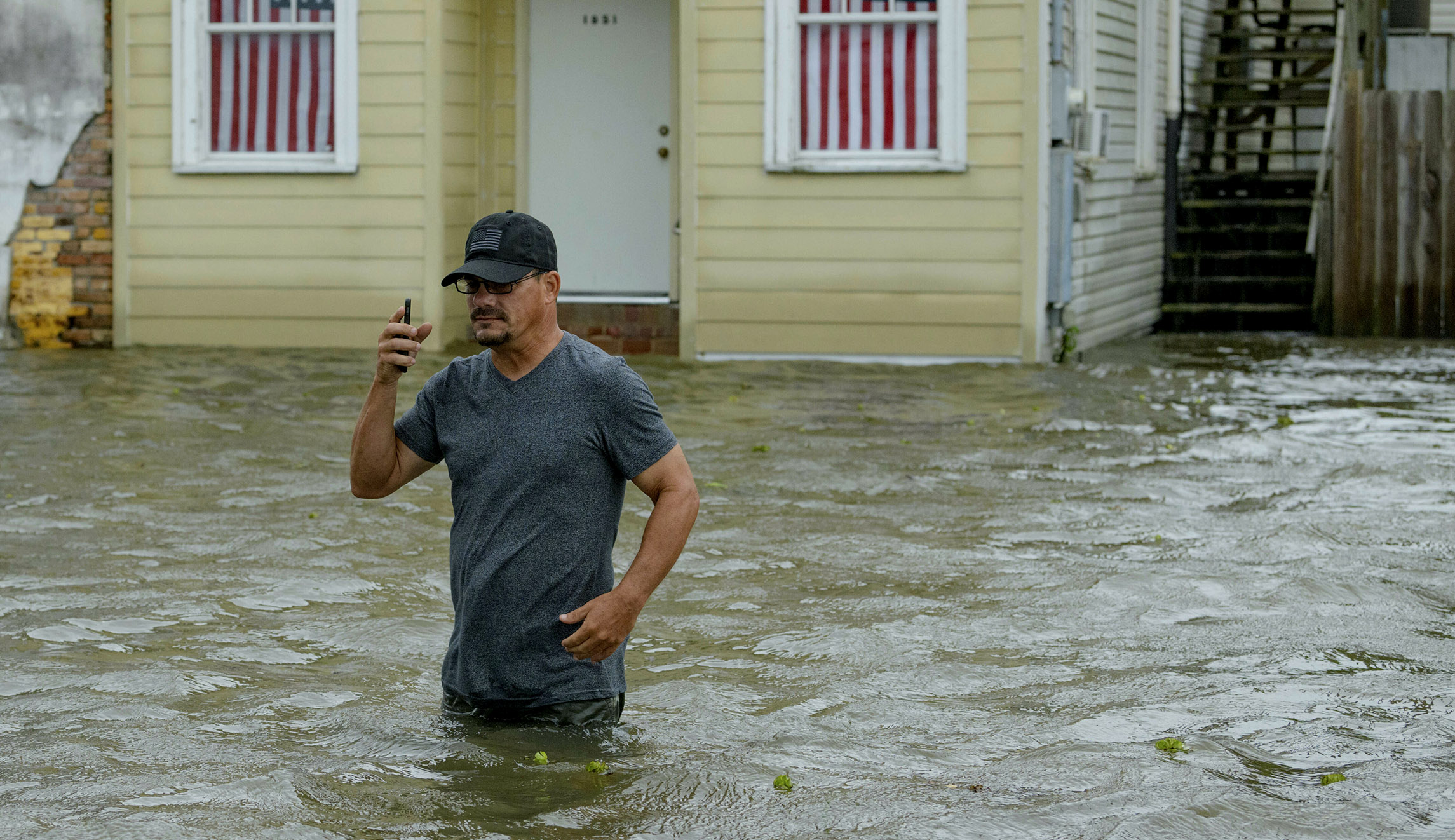 Barry Williams talks to a friend on his smartphone as he wades through storm surge from Lake Pontchartrain on Lakeshore Drive in Mandeville, Louisiana.