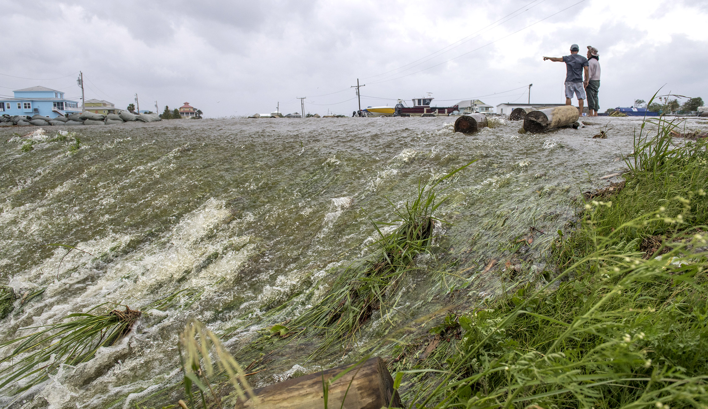 Chris Nguyen and his father, Trung, look at the moving water that breached the top of a levee in Plaquemines Parish just south of New Orleans as Barry makes landfall along the coast on Saturday.