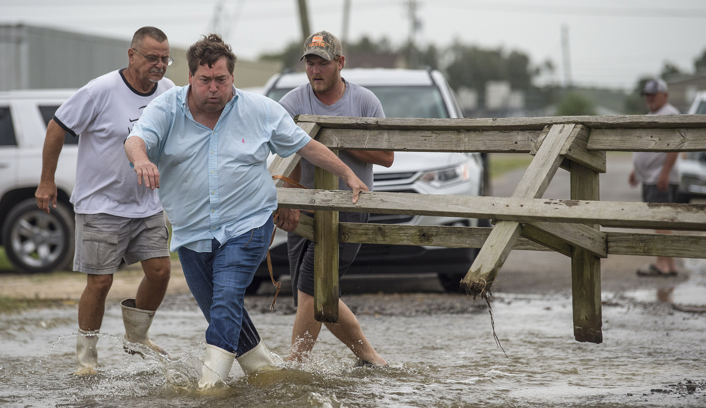 Louisiana Lt. Gov. Billy Nungesser, left center, helps move a wooden barricade to block a road where water was rising in Plaquemines Parish just south of New Orleans as Barry makes landfall along the coast on Saturday.