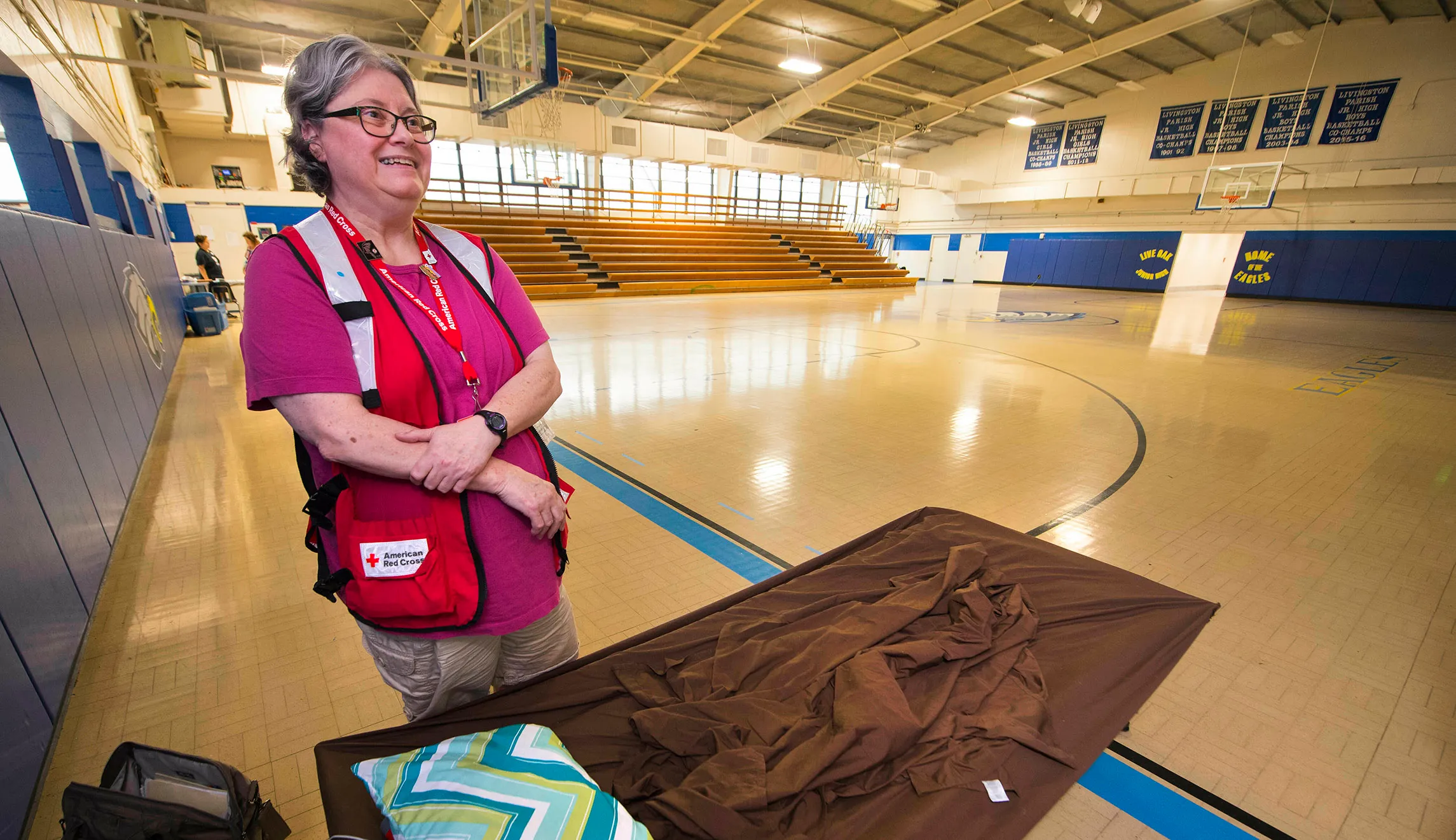 Richmond, New Hampshire's Alicia Drew, a volunteer with the American Red Cross, talks next to her cot inside Live Oak Junior High School's gymnasium, at a shelter there that she was managing for the Livingston Parish Office of Emergency Preparedness on Saturday.