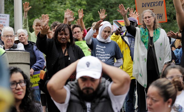 In this photo taken Wednesday, July 17, 2019, Jose Robles, front center, rests with his hands behind his head as supporters hold their arms toward him during a blessing before he presented himself to U.S. Immigration and Customs Enforcement officials in Tukwila, Wash. 