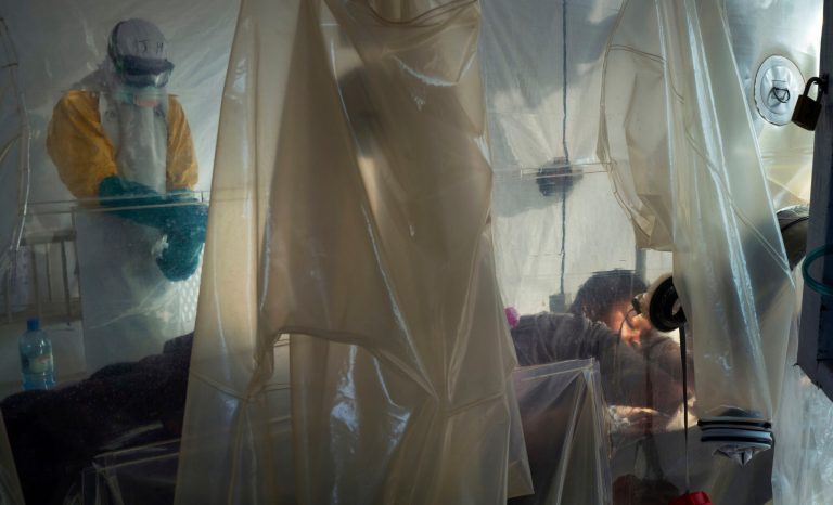 In this Saturday, July 13, 2019 photo, health workers wearing protective gear check on a patient isolated in a plastic cube at an Ebola treatment center in Beni, Congo. On July 17, the World Health Organization declared the Ebola outbreak an international emergency after it spread to eastern Congo's biggest city, Goma.